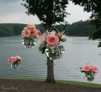 Hanging rose vases adorning wedding pergola